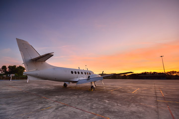 Fototapeta na wymiar Small aeroplane infront of aircraft hangar during sunrise