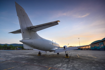Naklejka na ściany i meble Small aeroplane infront of aircraft hangar during sunrise