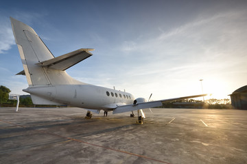 Small aeroplane infront of aircraft hangar during sunrise - obrazy, fototapety, plakaty