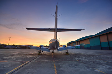 Small aeroplane infront of aircraft hangar during sunrise
