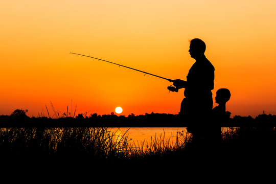 father and son fishing in the river sunset background