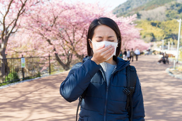 Woman feeling unwell with Pollen allergy under sakura tree