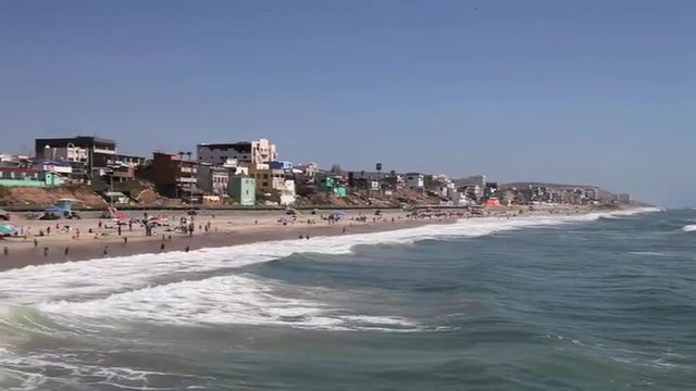 Panning shot across the U.S. border with Mexico onto a Tijuana beach.