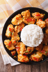 chicken in orange sauce with rice close-up on a plate. vertical top view
