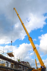 Industrial crane on a construction site lifting wooden panels