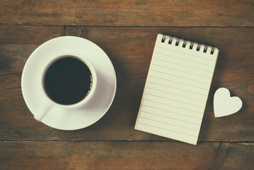 top view image of blank notebook next to cup of coffee. vintage filtered and toned
