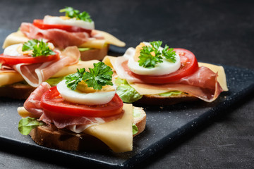 Delicious sandwich with prosciutto ham, cheese, tomato and egg