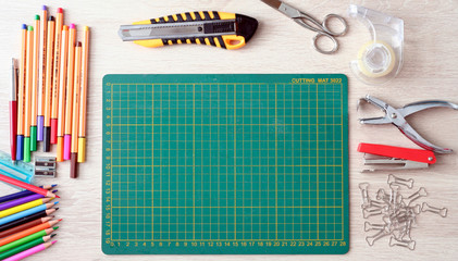 Desktop mockup, top view, with colorful stationery and cutting mat, on wooden background