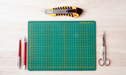 Desktop mockup, top view, with colorful stationery and cutting mat, on wooden background
