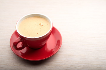 Red cup of coffee with frothy milk