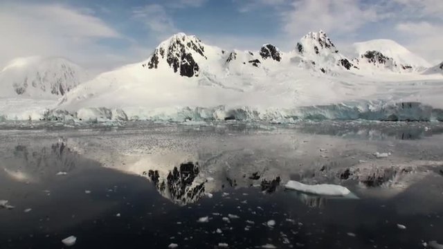 Moving Ice Floes and Ice Sheets in the calm Antarctic Sea, Reflection of Antarctica Mountain in water surface. Amazing beautiful views of Nature and landscape of snow, ice and white of Antarctic.