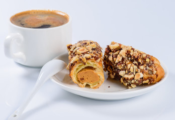 Eclair with nuts and a cup of coffee still life(shallow DOF)