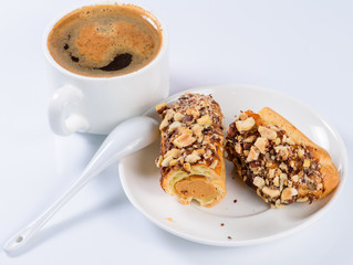 Eclair with nuts and a cup of coffee still life(shallow DOF)