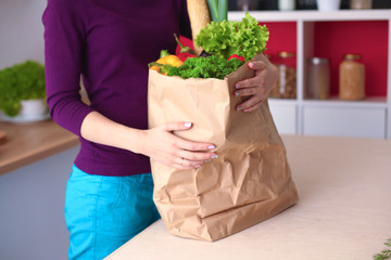 Healthy positive happy woman holding a paper shopping bag full of fruit and vegetables