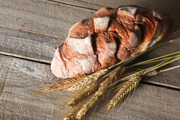 rustic crusty bread and wheat ears on a dark wooden table