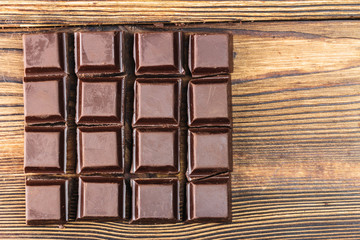 Dark chocolate cubes on wooden table, top view, close-up