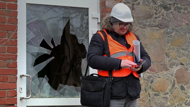 Building inspector with tablet PC near broken window
