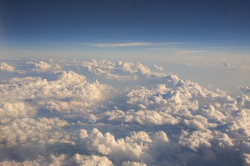 Fototapeta na wymiar Fluffy white clouds and blue sky seen from airplane