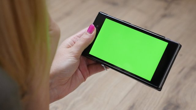 Woman holding green screen display mobile smart phone 4K 2160p 30fps UltraHD video - Female relaxing and looking to greenscreen mobile device 4K 3840X2160 UHD footage 