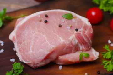 Sliced pieces of raw meat for barbecue with fresh Vegetables (tomatoes, lettuce) on wooden surface. Meat raw stacked on wooden background, beef Steak BBQ. 