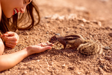 Excited woman feeding moorish squirrel on Fuerventura island in Spain