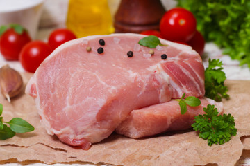 Sliced pieces of raw meat for barbecue with fresh Vegetables (tomatoes, lettuce) on wooden surface. Meat raw stacked on wooden background, beef Steak BBQ. 