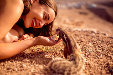 Excited woman feeding moorish squirrel on Fuerventura island in Spain