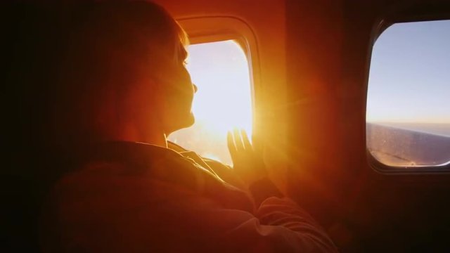 Young woman looking at the sun from the window of an airliner