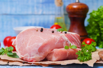 Sliced pieces of raw meat for barbecue with fresh Vegetables (tomatoes, lettuce) on wooden surface. Meat raw stacked on wooden background, beef Steak BBQ. 