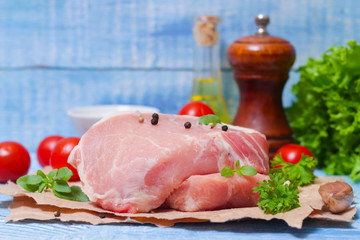 Sliced pieces of raw meat for barbecue with fresh Vegetables (tomatoes, lettuce) on wooden surface. Meat raw stacked on wooden background, beef Steak BBQ. 