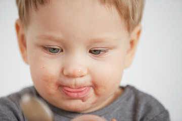 Cute little boy eating yogurt. Boy eating a fruit smoothie himself in the bedroom at the weekend , lazy morning, warm and cozy scene.