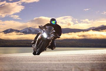 young man riding big bike motorcycle against sharp curve of asph