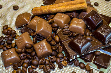 chocolate bar, coffee beans and cinnamon sticks on a sack background