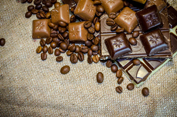 chocolate bar, coffee beans and cinnamon sticks on a sack background