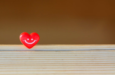 Red heart on a wooden background. Heart with a smile. Small hearts. Abstract background. Soft focus...