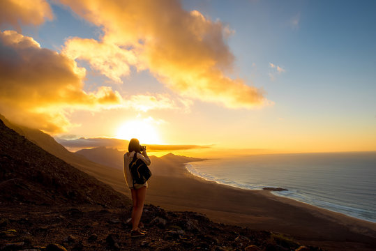 Beautiful seascape view on Cofete coastline with young female traveler on the sunset on Fuerteventura island in Spain. General plan with a lot of space