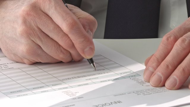 male hand in suit filling in invoice paper