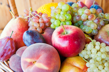 Fresh fruits in a basket: apple, peaches, pear, plums, nectarine, melon and grapes
