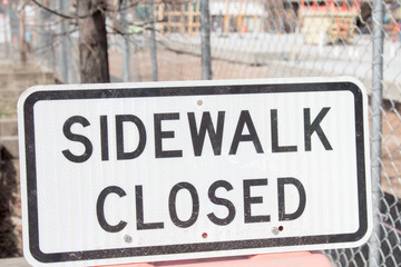 Obraz premium Sidewalk closed sign in front of a fence and construction zone