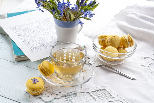 A cup of hot tea, flowers blue snowdrop, sketchbook and lemon macaroons on a light background