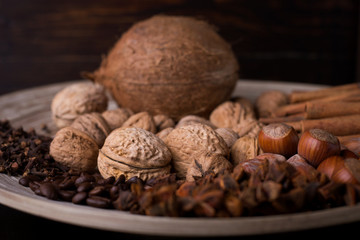 spices for baking, cinnamon sticks, star anise, cloves, nuts, coconut, coffee beans on a wooden background