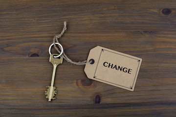 Key and a note on a wooden table with text - Change