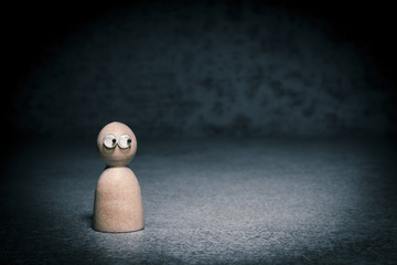 Symbol of loneliness and depression. Little figure alone in darkness looking nervous sideways....