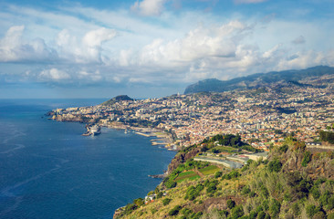 Fototapeta na wymiar Sunny day in tropical city of Funchal, Madeira, Portugal with blue ocean, few clouds and major cruise ship.
