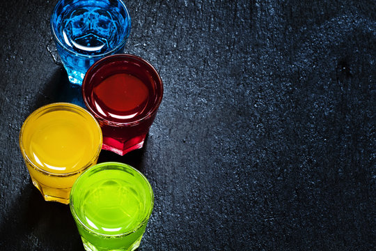 Multi-colored cocktails on a dark background, top view