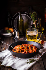 Stewed cabbage  in a vintage frying pan and a mug with beer.