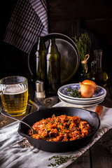 Stewed cabbage  in a vintage frying pan and a mug with beer.