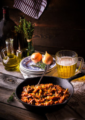 Stewed cabbage  in a vintage frying pan and a mug with beer.