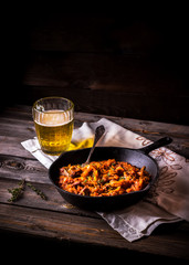 Stewed cabbage  in a vintage frying pan and a mug with beer.