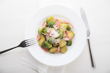 Brussels sprouts with bacon and parmesan on white background top view.